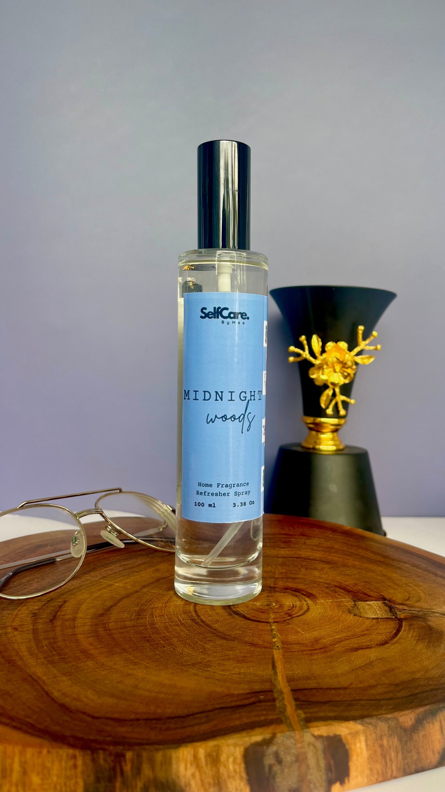 Perfume bottle labeled 'Midnight Woods' on a wooden surface with a gray background