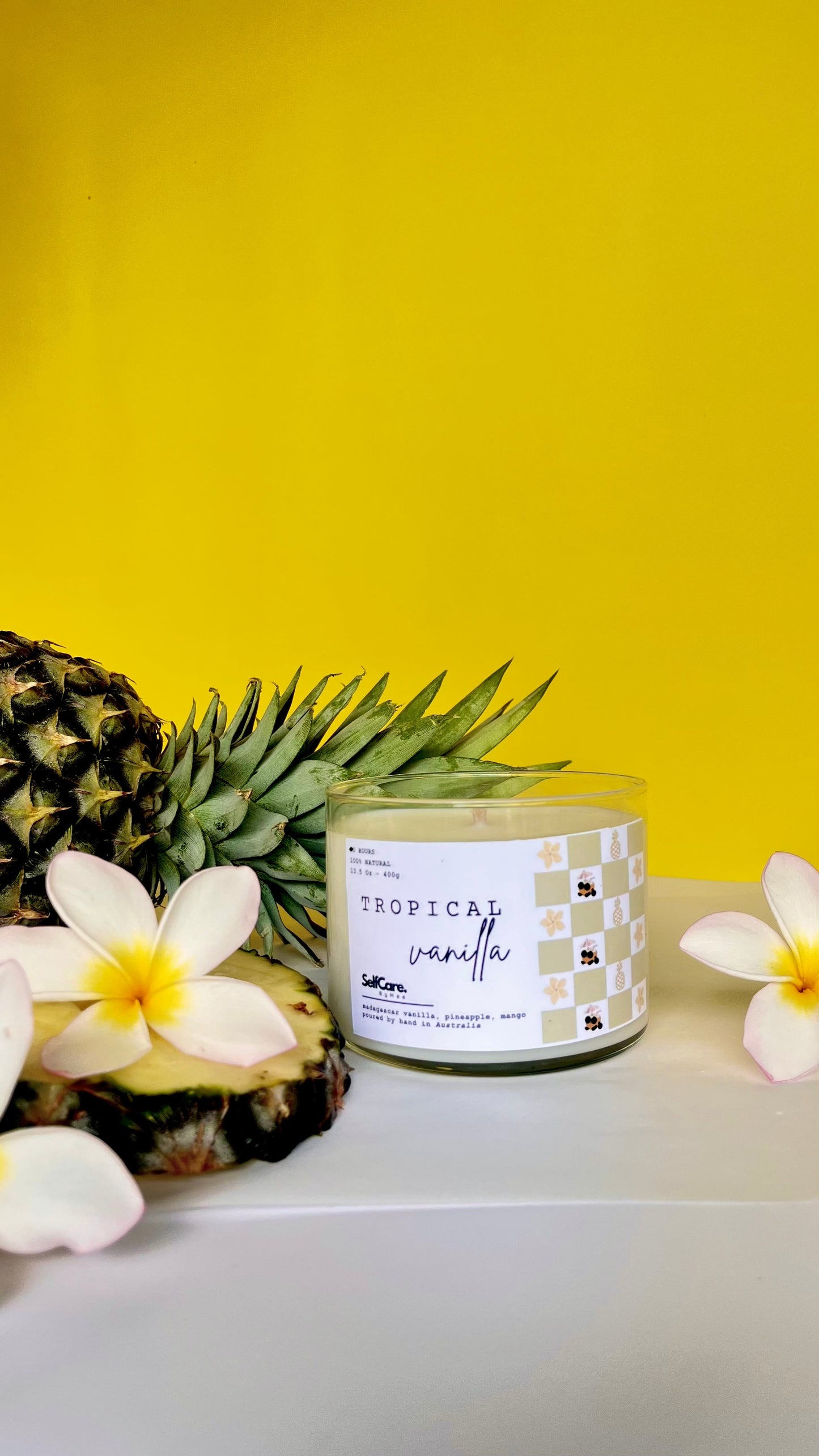 Tropical vanilla candle with a pineapple and flowers on a yellow background
