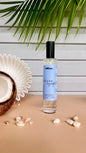 Perfume bottle labeled 'Azure Escape' on a wooden surface with coconut and shells, against a light wooden panel background.