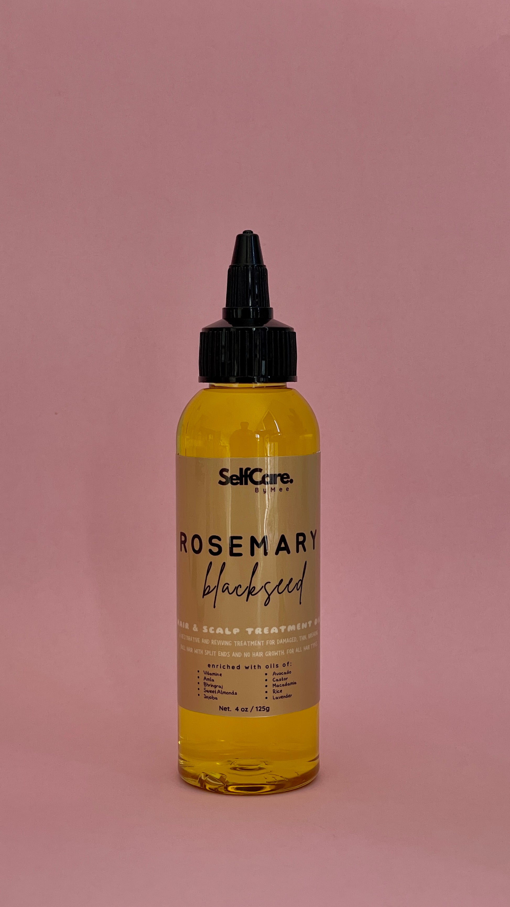 A bottle of SelfCare by Mee Rosemary Blackseed Scalp Treatment with a black dropper cap, filled with yellow oil, set against a solid dusty pink background.